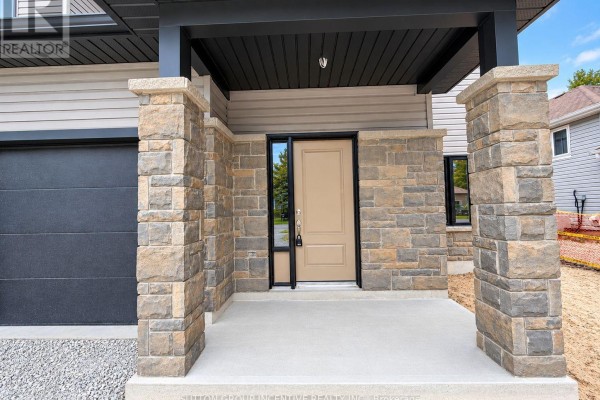 Close-up of the front entrance with stone pillars, a beige door, and a small window. - 9 - 1 Riverdale Drive, Wasaga Beach