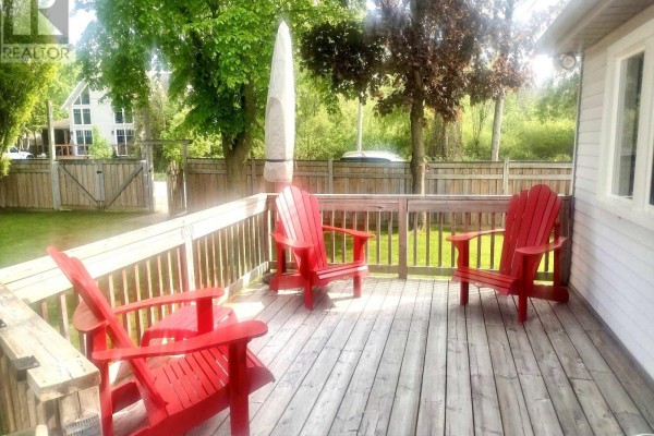 A small white cottage with a white awning over a screened-in porch and a wooden deck. - 9 - 1139 Claver Avenue, Innisfil