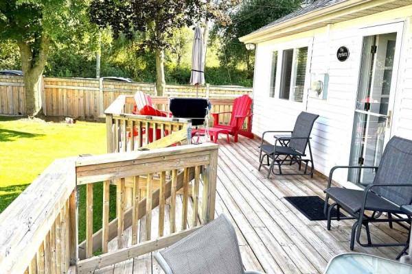 Lakeside view with a bench on the grass, a small dock, and boats in the distance. - 9 - 1139 Claver Avenue, Innisfil