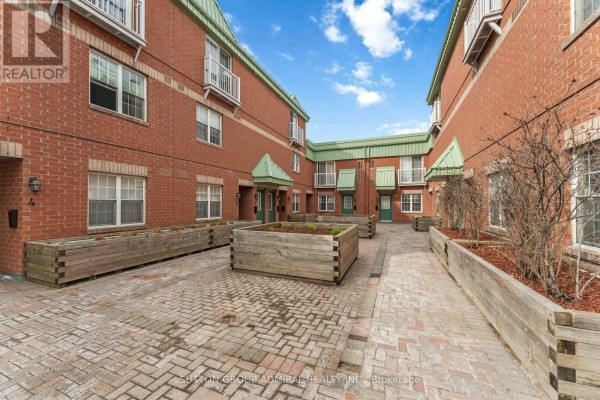 Courtyard view of the apartment building with brick paving and wooden planter boxes. - 9 - 130 Rochester Street, Ottawa