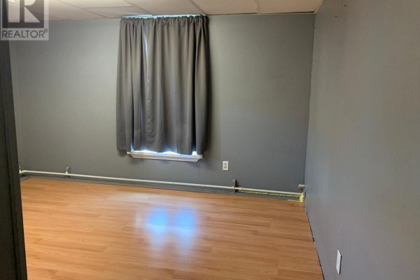 Empty room with grey walls, hardwood floor, and a large grey curtain covering a window. - 9 - 2 Bascom Street S, Uxbridge
