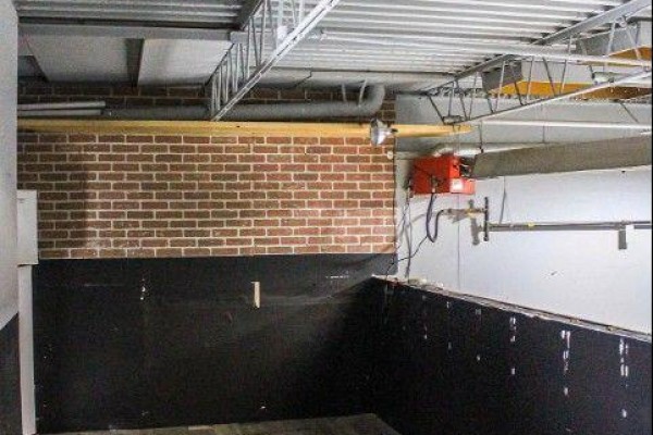 Detail of brick wall with exposed pipes and a red industrial heater. - 9 - 30 Canvarco Road, Toronto