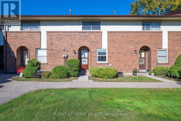 A kitchen with light wood cabinets, white appliances, black countertops, and a tiled floor. - 9 - 3665 Flamewood Drive, Mississauga