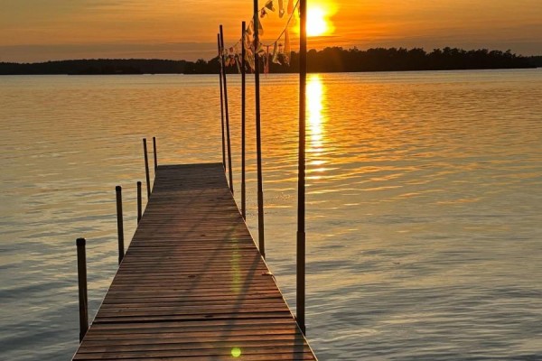Wooden dock extending into a calm lake during a vibrant orange sunset. - 9 - 422 Island View Road, Alnwick/haldimand