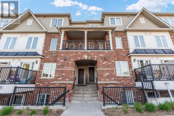 Exterior of a brick and vinyl townhouse complex with balconies, multiple windows, and parked cars in the lot. - 9 - 5 Armstrong Street, Orangeville