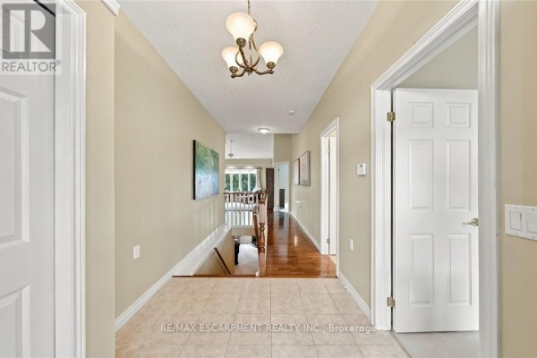 Interior hallway with tiled floor, hardwood floor at the end, and doors to rooms. - 9 - 500 Lakeview Drive, Woodstock