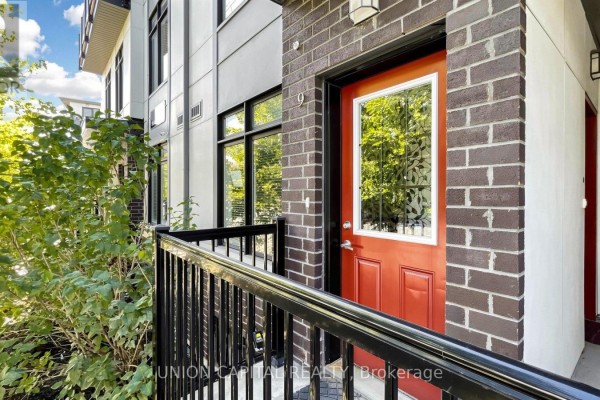 Close-up of a red townhouse entrance door with a glass window and brick surround. - 9 - 6 Bicknell Avenue, Toronto