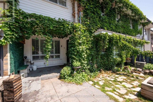 Close-up of townhouse entrance with stone patio and overgrown ivy. - 9 - 61 Ardglen Drive, Brampton
