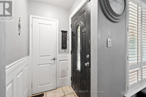 Interior entryway with black front door, white doors, and gray walls. - 9 - 61 Ardglen Drive, Brampton