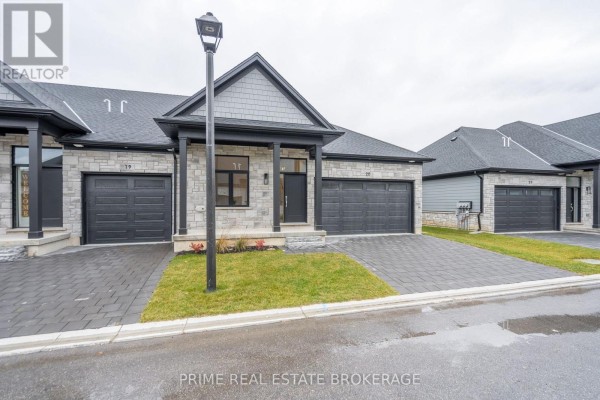 Close-up of the front entrance of a townhouse featuring a dark grey door, stone facade, and black porch columns. - 9 - 62 Compass Trail, Central Elgin