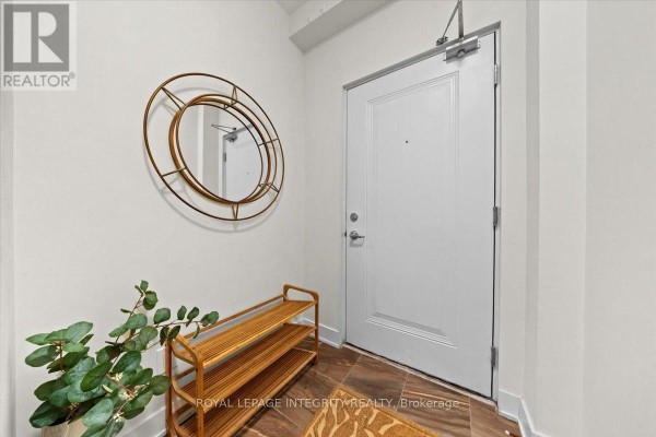 Entrance hallway with white door, round mirror, and a wooden shoe rack against a white wall. - 9 - 78 Holmwood Avenue, Ottawa