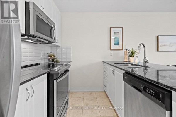 Kitchen view with white cabinets, granite countertops, stainless steel appliances, and a tiled backsplash. - 9 - 78 Holmwood Avenue, Ottawa