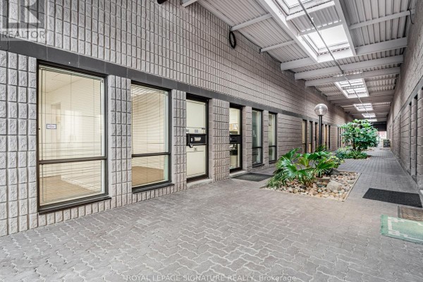 Exterior hallway with skylights and planters. Features brick walls and multiple unit doors. - 9 - 85 Ferrier Street, Markham