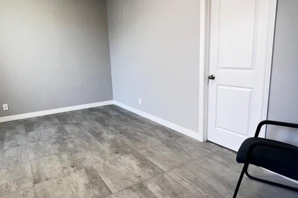 Empty office room with light grey walls, beige tile floor, and a closed white door. - 9 & 10 - 6731 Columbus Road, Mississauga