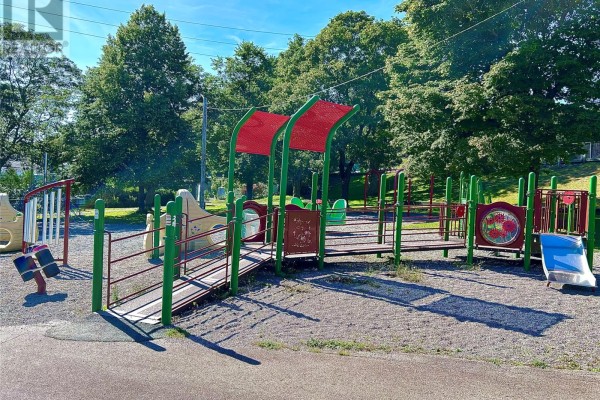 Colorful playground structure with slides, ramps, and swings on a gravel surface. - 9-11 Angel Place, St  John S
