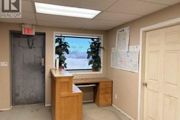 Reception desk with a computer and a window displaying plants and the exterior view. - 9 113 4th Street, Kindersley