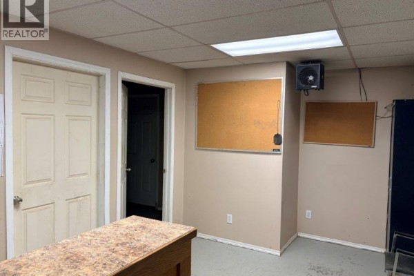 Interior office space with two doors, cork boards on the wall, and a ceiling light fixture. - 9 113 4th Street, Kindersley