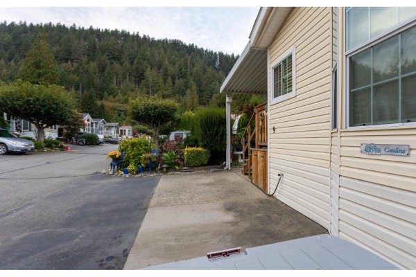 Mobile home with cream siding and a covered walkway, surrounded by evergreen trees. - 9 14600 Morris Valley Road, Mission