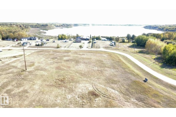 Aerial view of the lot with a road and nearby buildings, with a lake in the distance. - 9 Bechthold Bay 104, 191054 Twp 852, Rural Athabasca County