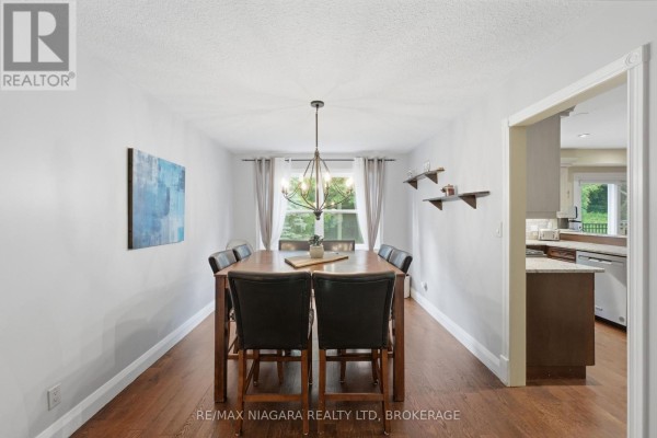 Dining room with light grey walls, a large wooden table with black chairs, and a chandelier. - 9 Beechnut Court, Pelham