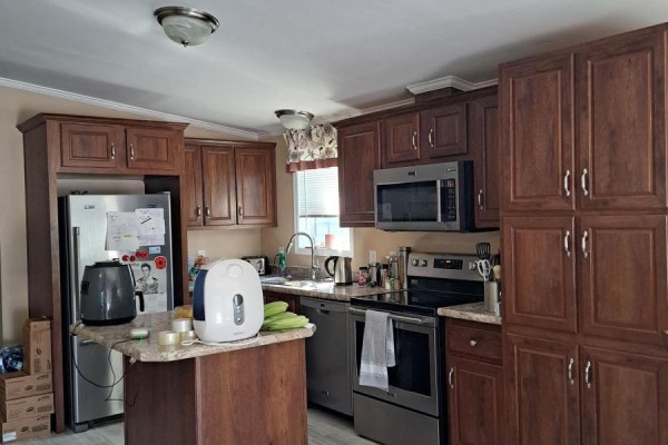 Kitchen with dark wood cabinets, stainless steel appliances, and a center island with a granite countertop. - 9 Bond Street, Strathroy Caradoc