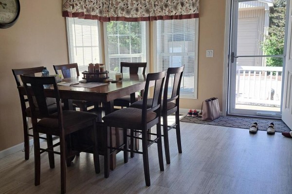 Dining area with a wooden table and chairs, next to a window and the front door. - 9 Bond Street, Strathroy Caradoc