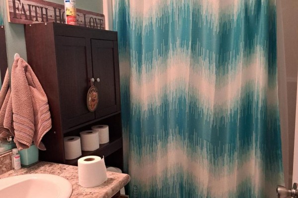 Bathroom with a granite countertop, sink, and a teal and white chevron shower curtain. - 9 Bond Street, Strathroy Caradoc