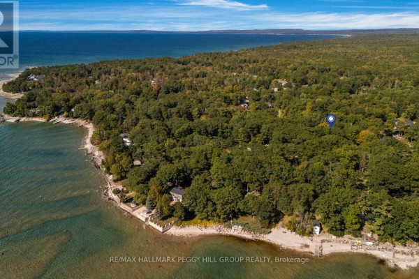 Aerial view of the property surrounded by dense trees, situated near a large body of water. - 9 Cabell Road, Tiny
