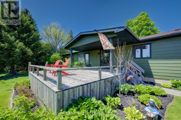Close-up of the wooden deck with red chairs, surrounded by green landscaping and a covered porch. - 9 Cardinal Street, Brockton