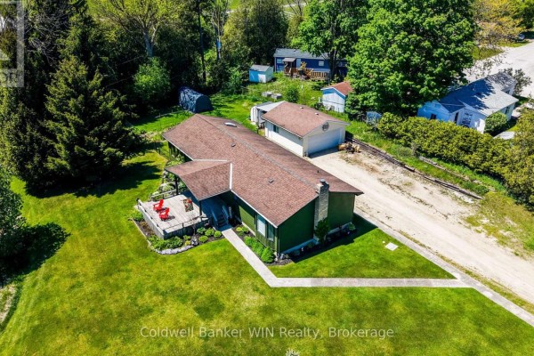 Aerial view of the green house with a pitched roof, a detached garage, and surrounding trees. - 9 Cardinal Street, Brockton