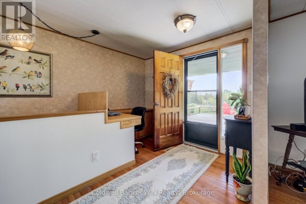 Interior view of the home's entrance with a wooden door, desk area, and a view of the deck. - 9 Cardinal Street, Brockton