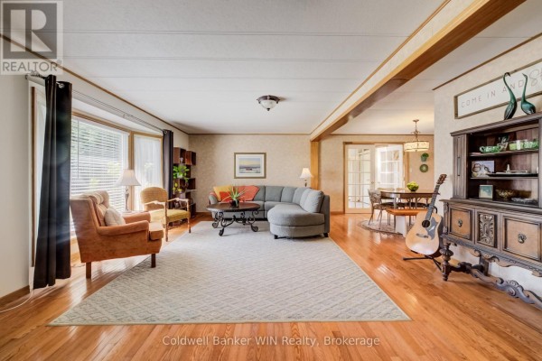 Spacious living room with a large sectional sofa, fireplace, dining area, and wood floors. - 9 Cardinal Street, Brockton