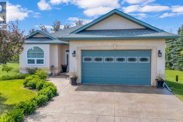 Front exterior of a cream-colored house with a blue garage door and arched window. - 9 Creek Road, Rural Ponoka County