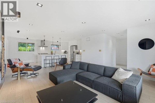 Open-concept living and dining area with large grey sectional sofa and white cabinetry. - 9 Donlea Drive, Hamilton