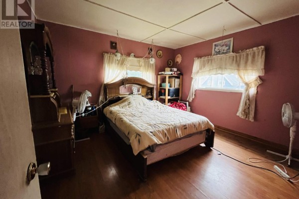 Bedroom with a large bed, wooden dresser, and pink walls with a window. - 9 Dundonald Street, Amherst