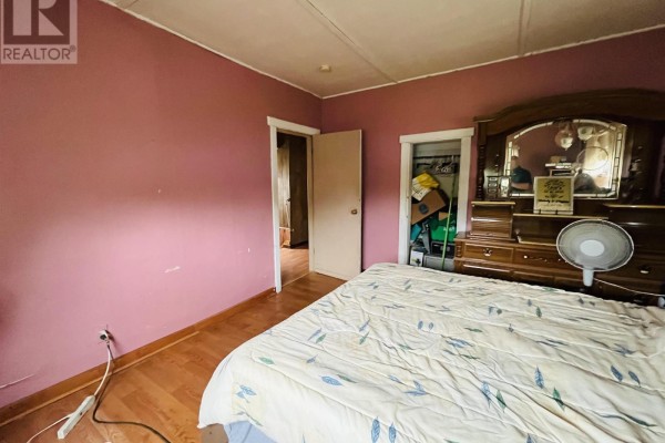Bedroom with pink walls, large bed, open closet, and wooden dresser. - 9 Dundonald Street, Amherst