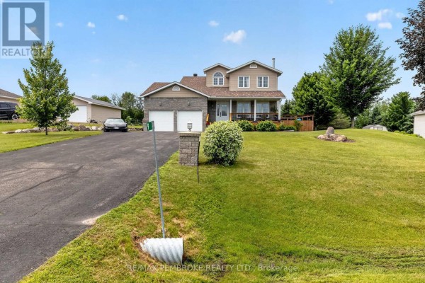 View of the front of the house from the driveway, showing landscaping and a stone pillar. - 9 Heron Drive, Laurentian Valley