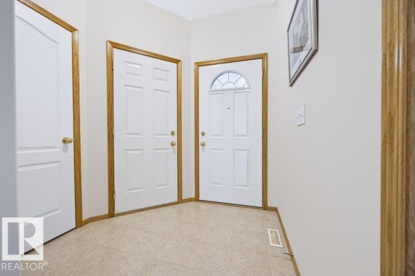 Interior entryway with beige tiled floor and two white doors with gold knobs. - 9 Hillcrest Co, Spruce Grove