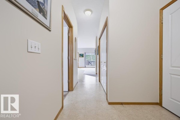 Hallway with beige tiled floor, cream walls, and access to multiple rooms. - 9 Hillcrest Co, Spruce Grove