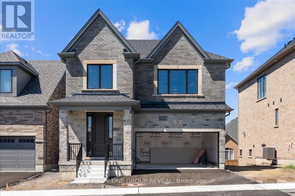 Front exterior of a grey stone and brick home with a dark front door and an open garage. - 9 Holland Street, Port Hope
