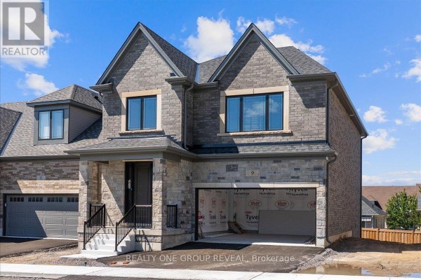Front exterior of a grey stone and brick home with a dark front door and an open garage. - 9 Holland Street, Port Hope