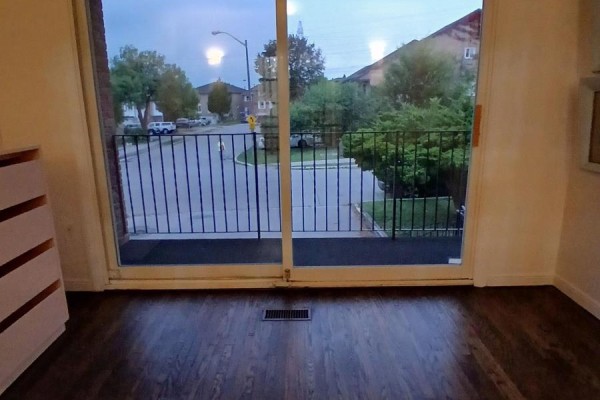 View from inside a room looking out onto a street and houses through sliding glass doors. - 9 Ivan Nelson Drive, Toronto