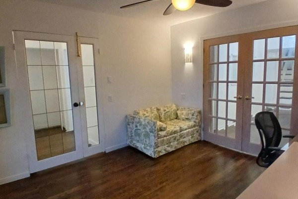 A living room with a floral sofa, wooden floors, and French doors. - 9 Ivan Nelson Drive, Toronto