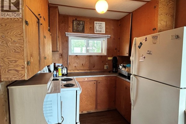 Compact kitchen with wooden cabinetry, stove, and refrigerator - 9 Kilcare Drive, Jackfish Lake
