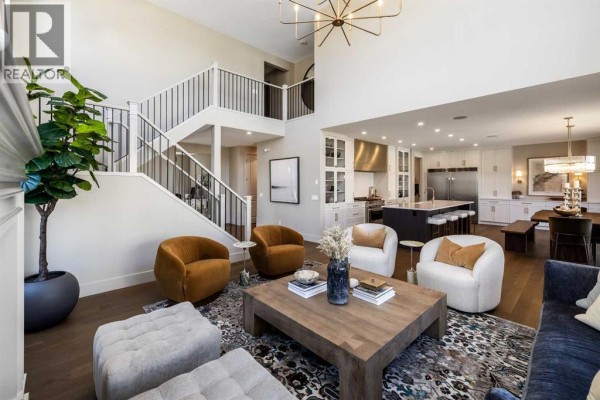Spacious living area with a grand staircase, modern furniture, and view into the kitchen. - 9 Legacy Vista Rise Se, Calgary