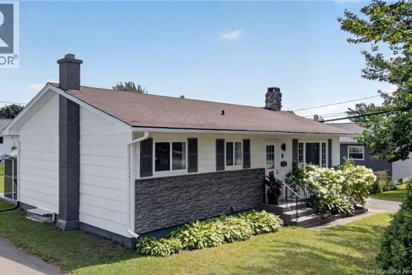 Side exterior view of the white bungalow showing a dark grey chimney. - 9 Magellan Drive, Moncton