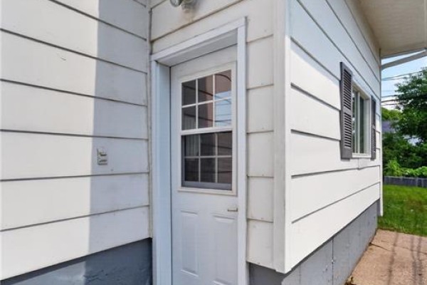 Close-up view of a white door with a small window on the bungalow exterior. - 9 Magellan Drive, Moncton