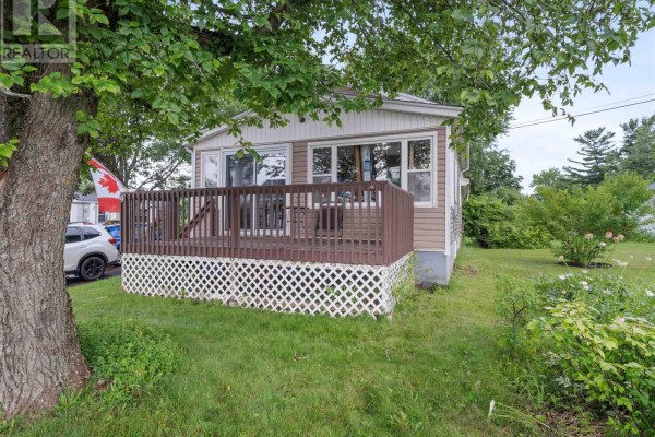 View of a wooden deck with a small table and chair, next to house siding. - 9 Main Street East, Stewiacke
