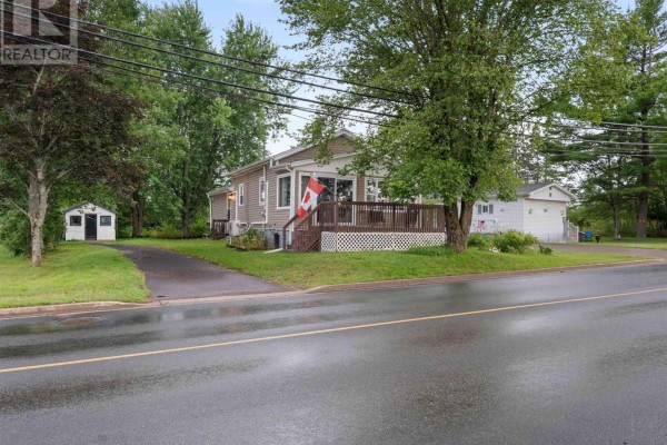 Right side view of a beige house with a Canadian flag on the deck railing. - 9 Main Street East, Stewiacke