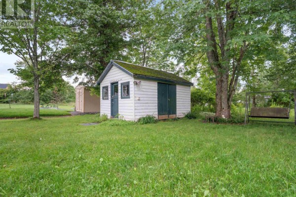 Two outdoor storage sheds in a grassy yard with trees and a swing set. - 9 Main Street East, Stewiacke